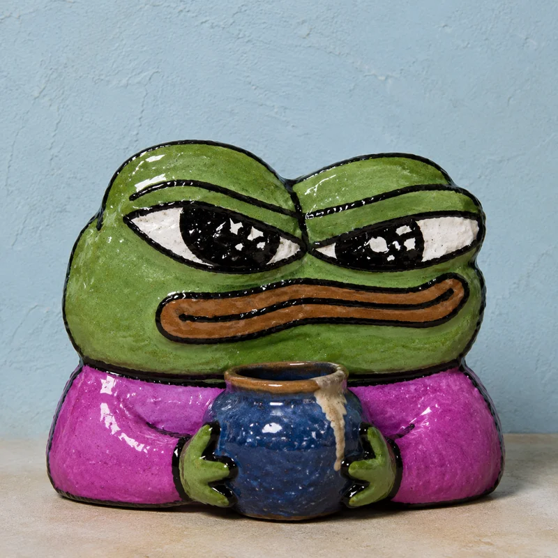 Ceramic BOME frog holding a freshly glazed blue pot